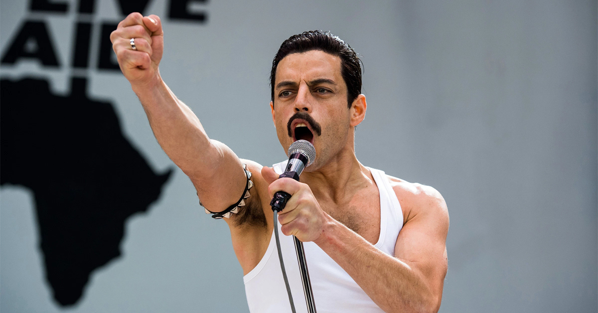 rami malek as freddie mercury in bohemian rhapsody singing at live aid with his fist in the air