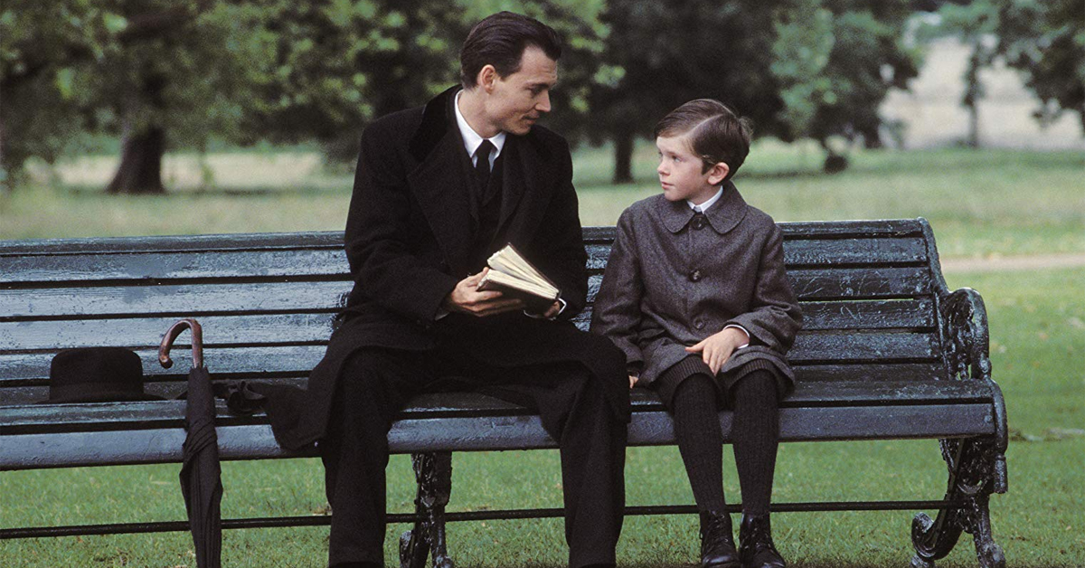 johnny depp holding a book and sitting on a bench with freddie highmore on finding neverland set