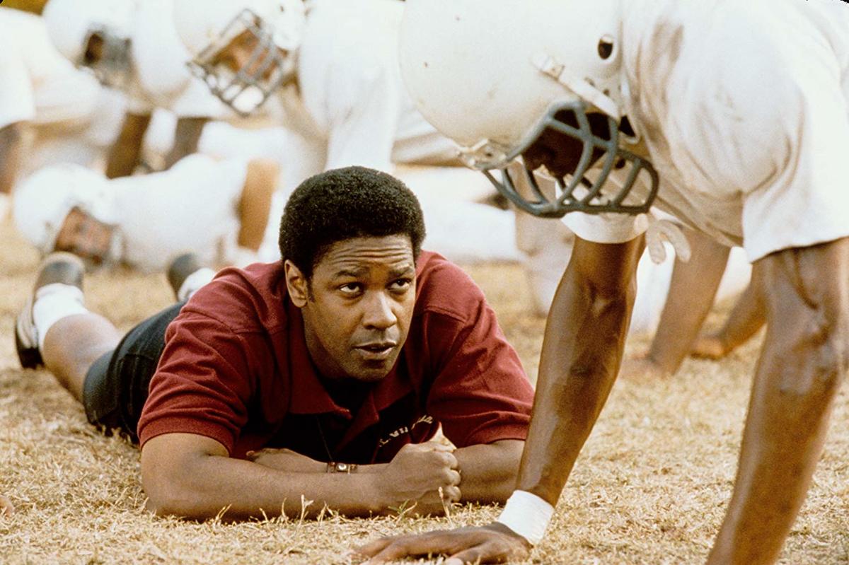 denzel washington laying on a football field with players in remember the titans
