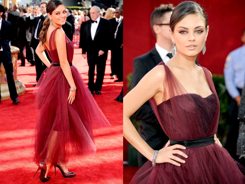 Mila Kunis wears a maroon gown layered in matching tool.