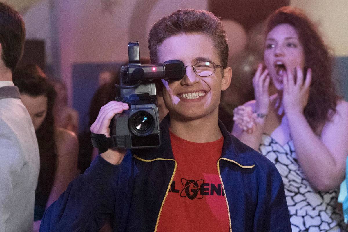 a boy holding up a retro camcorder