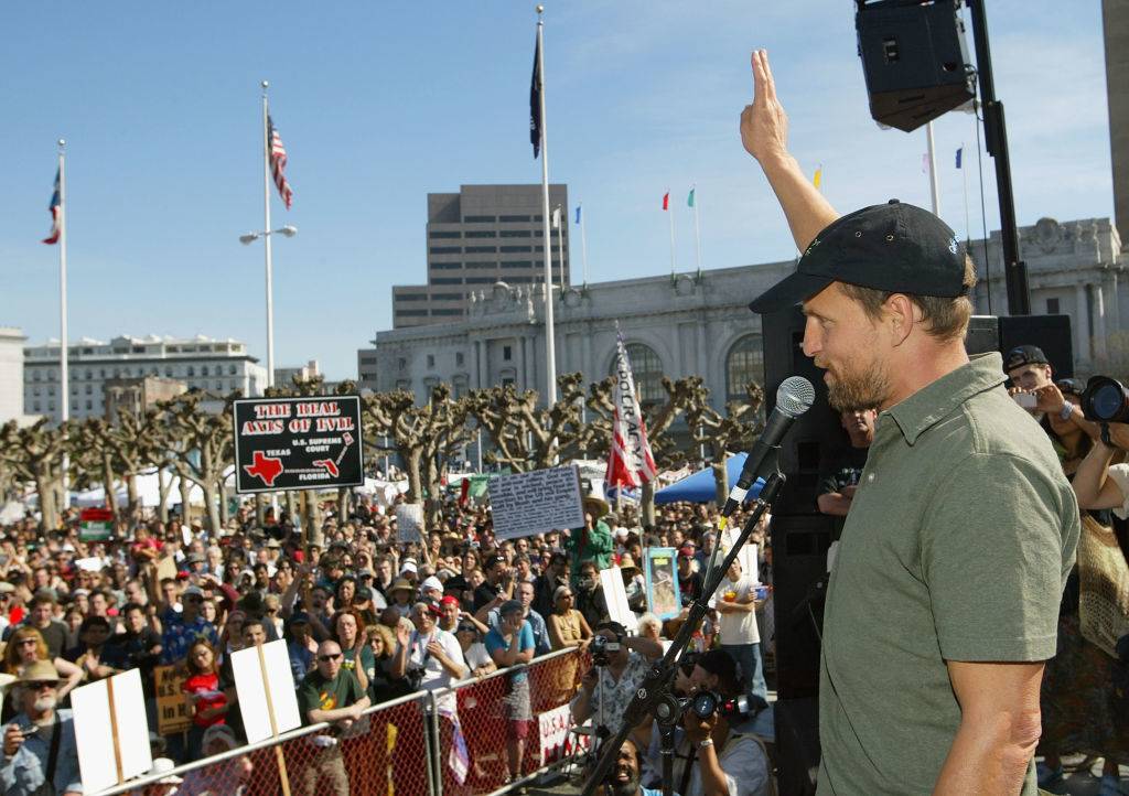 Actor Woody Harrelson flashes the peace sign to the crowd during an anti-war demonstration