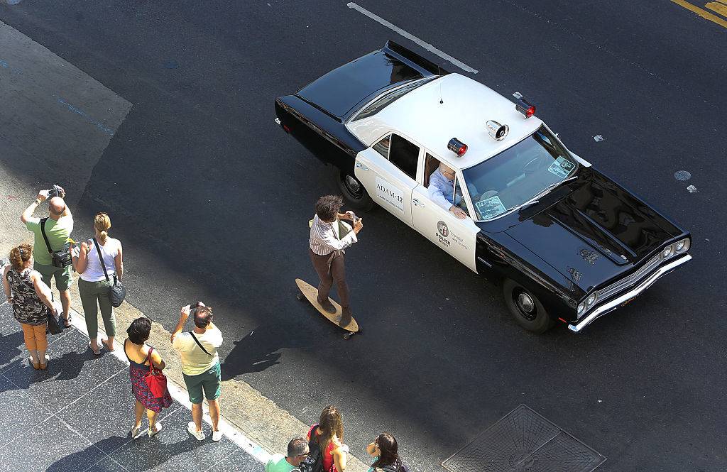 A skateboarder photographs a 1972 AMC Matador vehicle