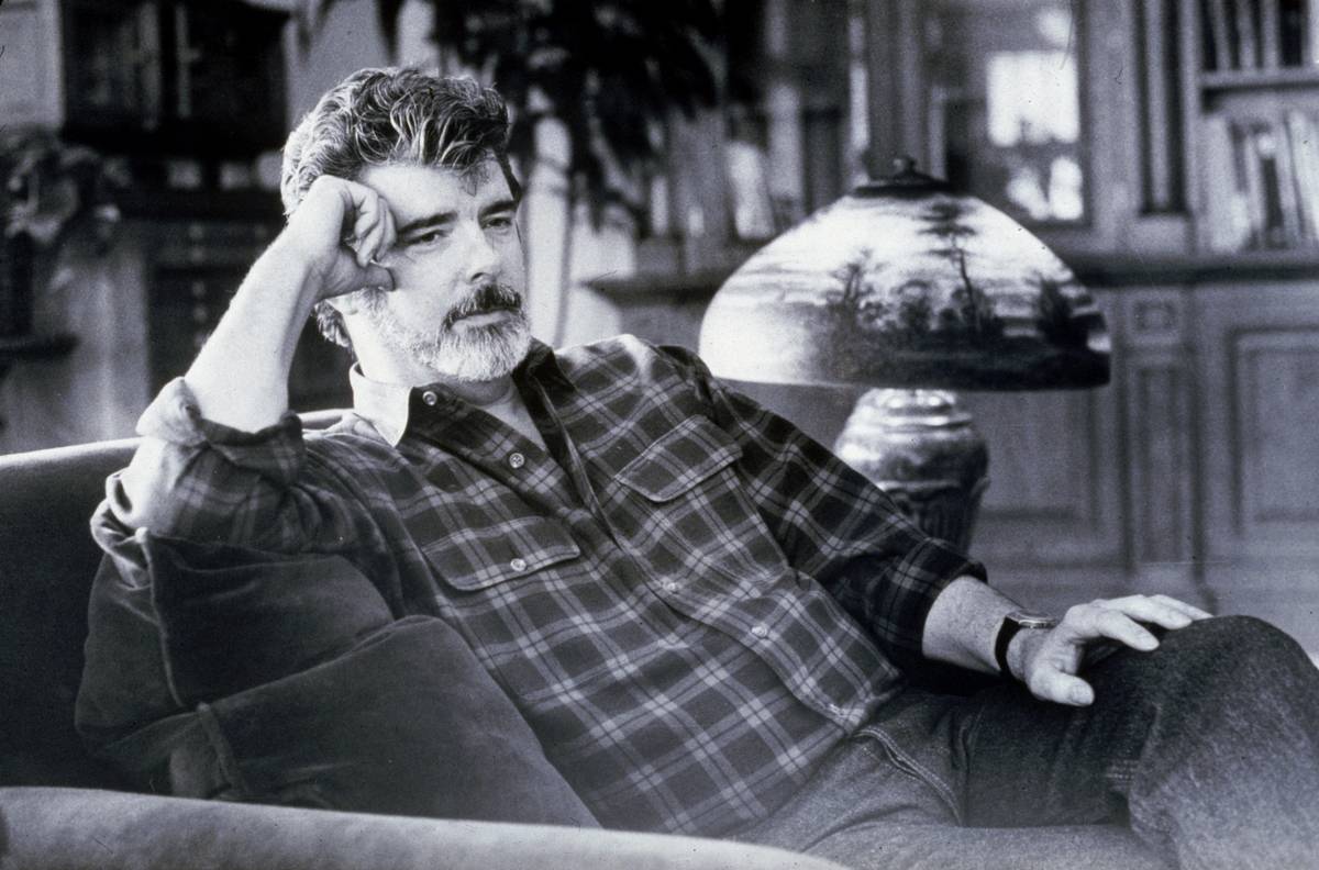 George Lucas lounges in a chair.