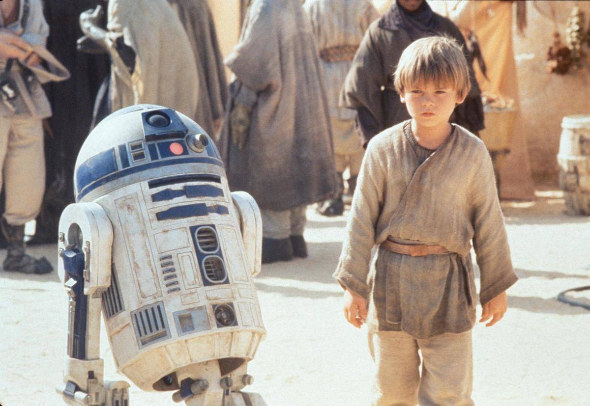 Jake Lloyd in character as Anakin Skywalker standing with R2-D2 for The Phantom Menace