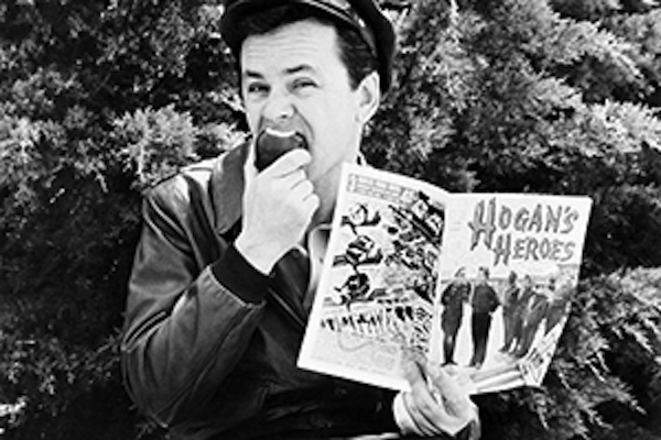 Bob Crane eats apple and holds Hogan's Heroes comic book up