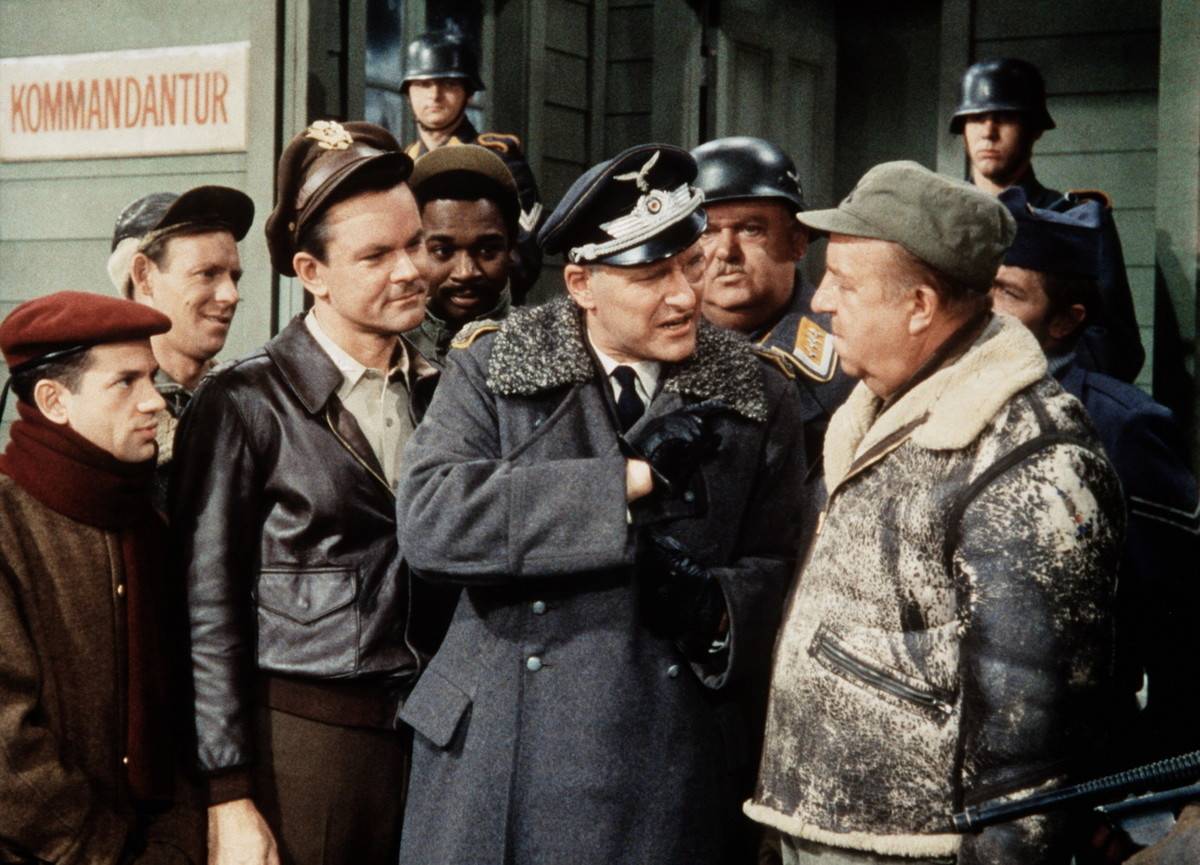 General wears gloves, points at other character in scene from Hogan's Heroes