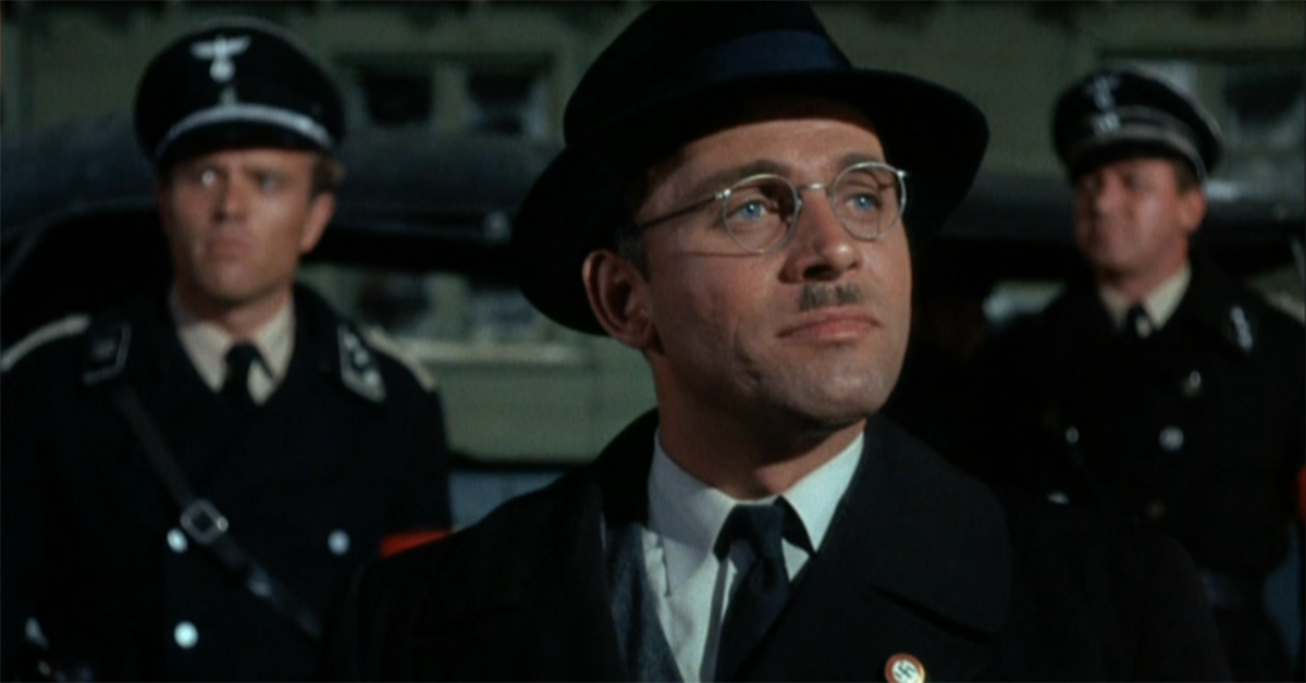 Scene from Hogan's Herpes, man in brimmed hat, glasses, and tie