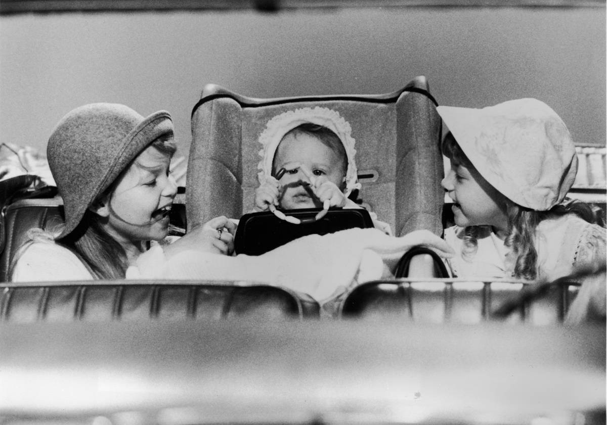L-R: Actor Candace Cameron (L) and Jodie Sweetin smile at a baby (played by either Mary-Kate or Ashley Olsen) in a still from the television series, 'Full House,' circa 1987.
