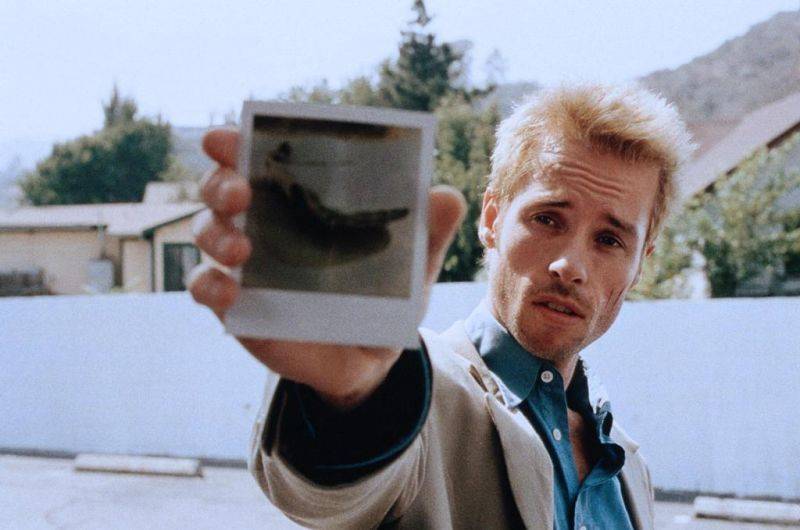 Guy Pearce holding up Polaroid photograph in [redacted]