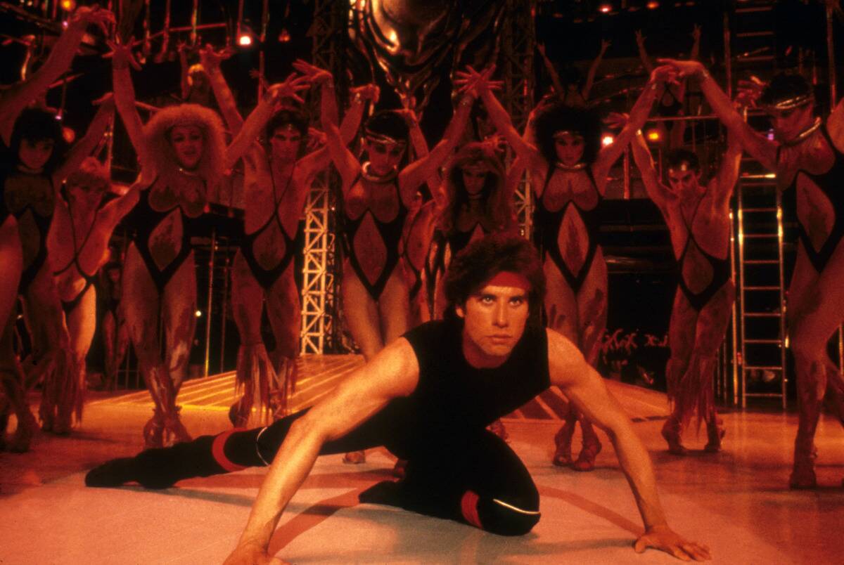 John Travolta dancing on stage next to chorus as Tony Manero in Staying Alive