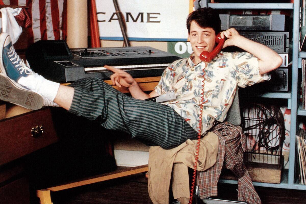 Matthew Broderick reclining and talking on phone while stroknig keyboard as Ferris Bueller in Ferris Bueller's Day Off