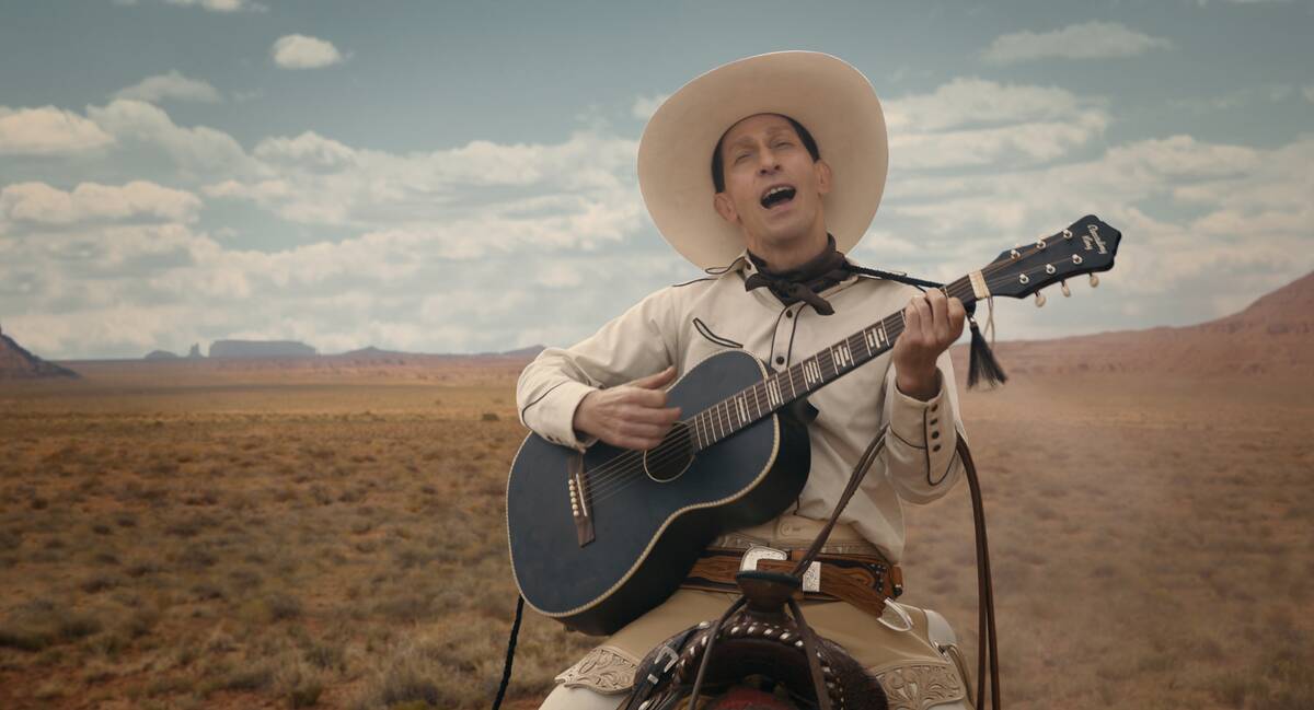 Tim Blake Nelson riding horse playing guitar and singing in white cowboy outfit in The Ballad of Buster Scruggs
