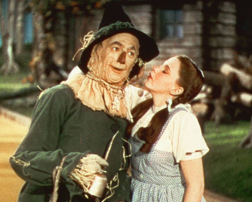 Judy Garland as Dorothy Gale standing next to Ray Bolger as the Scarecrow with her eyes closed in The Wizard of Oz