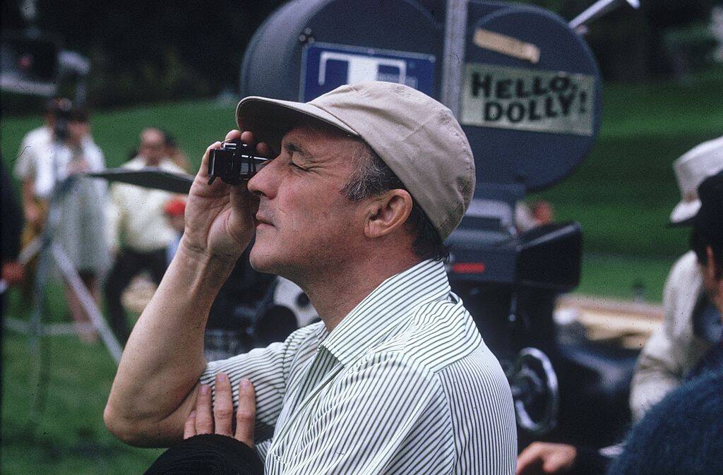 gene kelly peers through an eye-glass whilst directing hello dolly