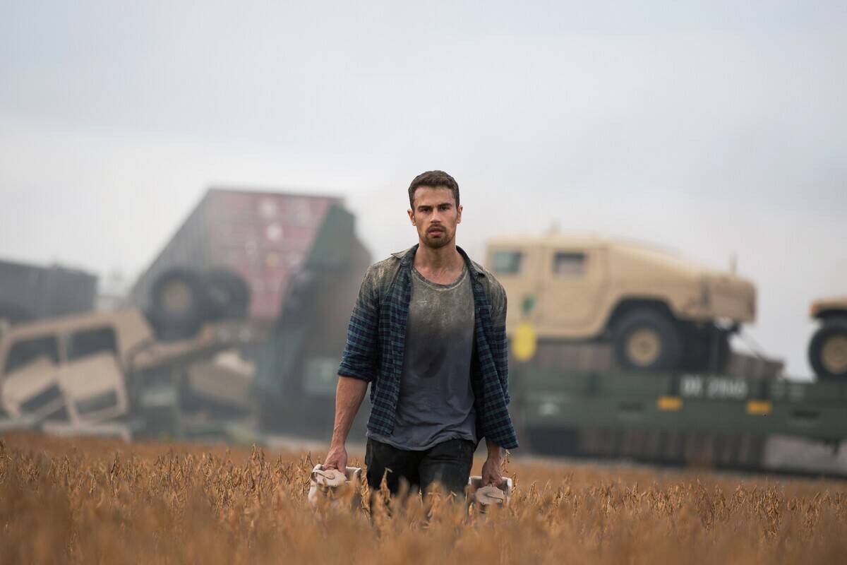 Man standing in field with junk behind him in How It Ends